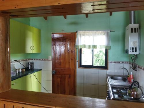 uma cozinha com paredes verdes, um fogão e uma janela em Cabaña Los Lagos em Puerto Montt