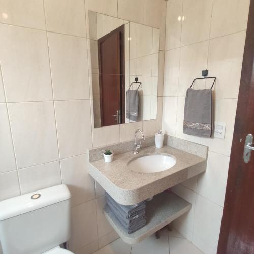 y baño con lavabo, aseo y espejo. en Casa de 2 Quartos na Praia da Joaquina, en Florianópolis