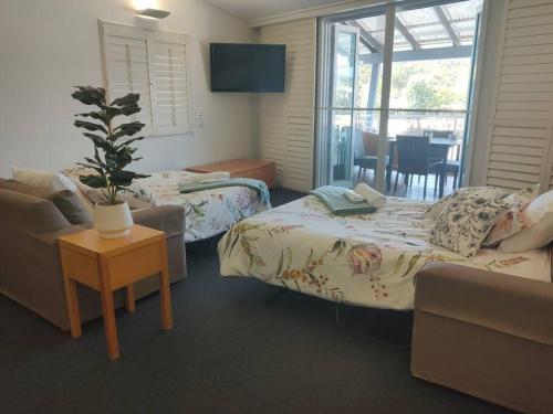 Zimmer mit 2 Betten, einem Sofa und einem Tisch in der Unterkunft Spacious Waterfront Apartment Couran Cove in South Stradbroke