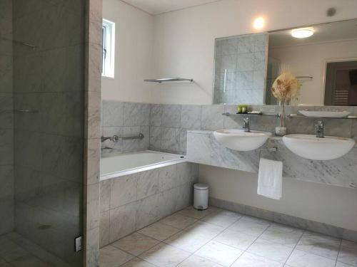 y baño con 2 lavabos, bañera y espejo. en Spacious Waterfront Apartment Couran Cove, en South Stradbroke