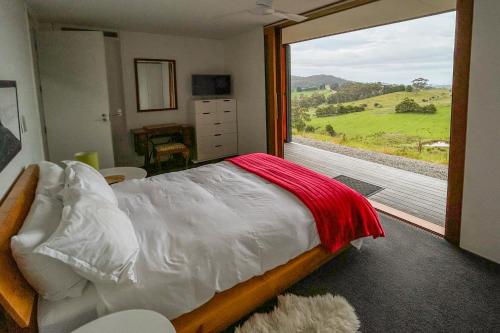 een slaapkamer met een bed en een groot raam bij The Orange House in Premaydena