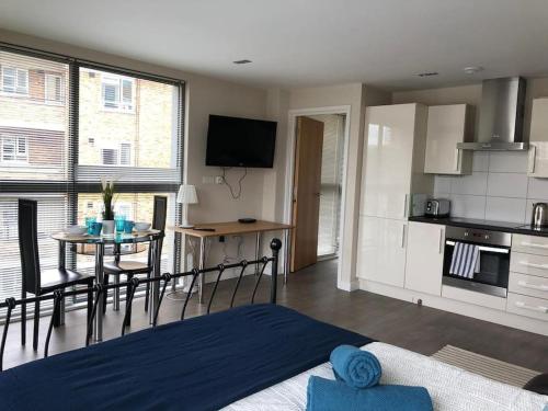 a living room with a kitchen and a table with chairs at STUDIO Apartment opposite shoreditch Park in London