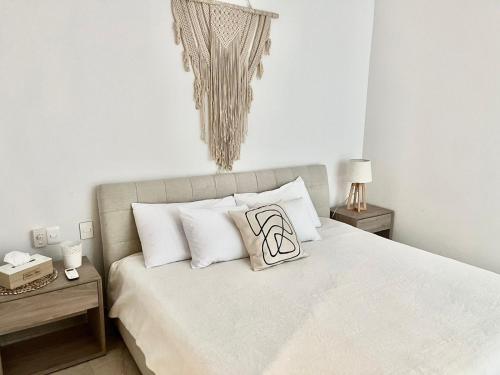 Un dormitorio con una cama blanca con almohadas. en Luxury 5th Avenue Menesse 32, en Playa del Carmen