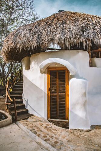 a small house with a thatched roof and stairs at New Ruins Off-The-Grid SuperAdobe Domes with Pool in San Francisco de Abajo