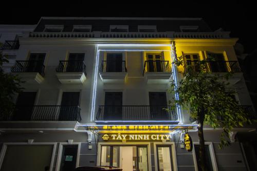 TÂY NINH CITY HOTEL في Tây Ninh: مبنى أبيض كبير مع علامة مينيفان المدينة لسيارات الأجرة عليه