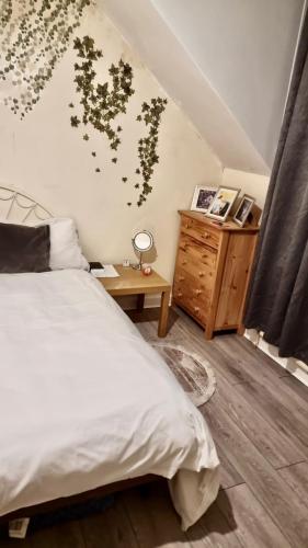 a bedroom with a white bed and a wooden dresser at Centrally located Double Bedroom in Leeds in Hunslet