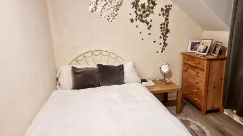a bedroom with a white bed and a wooden dresser at Centrally located Double Bedroom in Leeds in Hunslet