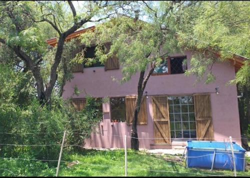 een roze huis met een boom ervoor bij Cabaña Thaqu in Merlo