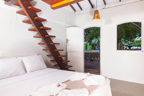 1 dormitorio con cama blanca y escalera de caracol en Pousada da Praça Caraíva, en Caraíva