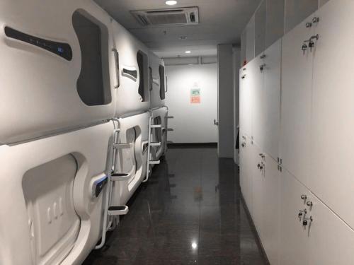 un corridoio con una fila di lavatrici e asciugatrici di Capsule Inn a Kota Kinabalu
