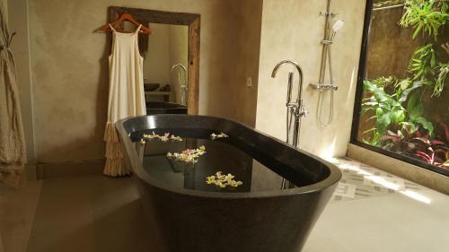 a bath tub with flowers in it in a bathroom at Chakra Living Ubud in Ubud