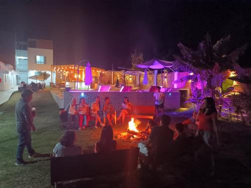 un grupo de personas sentadas alrededor de un fuego por la noche en HOTEL MAR Y LAGO, en Lunahuaná