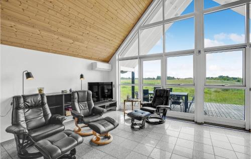 a living room with chairs and a tv and windows at Holiday Home Nordstrup Xii in Rømø