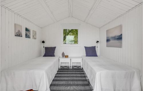 3 Bedroom Beach Front Home In Vig في Vig: سريرين في غرفة بجدران بيضاء ووسائد زرقاء