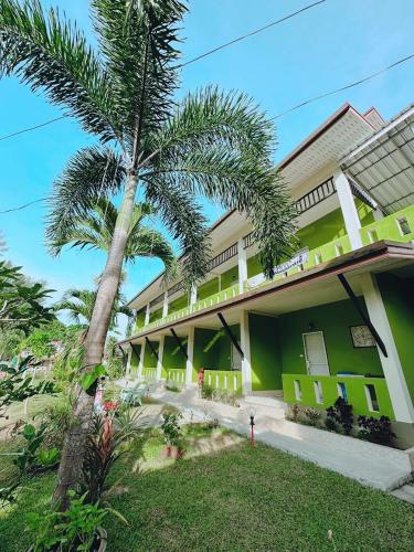 a building with a palm tree in front of it at FairHouse khaolak in Khao Lak