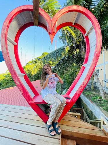 a woman sitting in a giant heart on a boardwalk at Bahia Azul Apartment in Six Huts