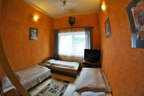 a room with two beds and a tv and a window at Gościniec Głuchołazy Zdrój in Głuchołazy