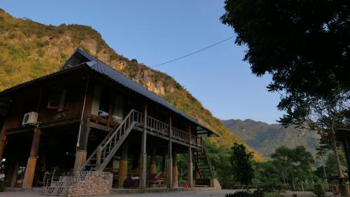 a large building with a mountain in the background at Nha Tan - Mai Chau Homestay and Tours in Mai Châu