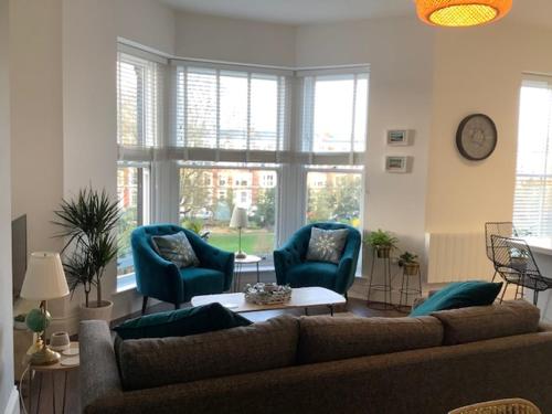 a living room with a couch and two blue chairs at Brooklands Hideaway in Scarborough