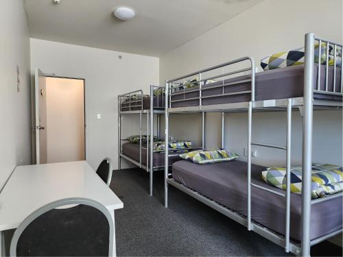 a room with two bunk beds and a table at Newton Lodge Auckland in Auckland