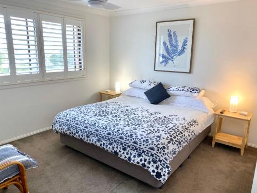 a bedroom with a bed with a blue and white comforter at Bermagui Beach Apartment in Bermagui