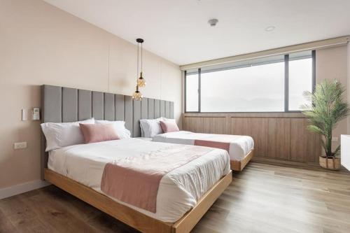 1 dormitorio con 2 camas y ventana grande en Suite - Go living & Suites, en Medellín