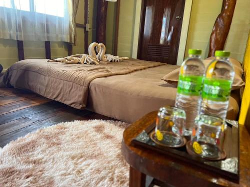 a bedroom with a bed and a table with bottles of water at Bankruchaem Homestay Kohpu in Ban Klang