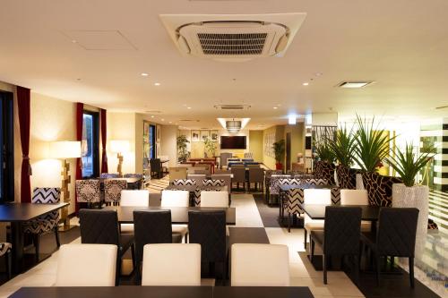 un ristorante con sedie e tavoli bianchi e una tavola di Centurion Hotel Grand Kobe Station a Kobe