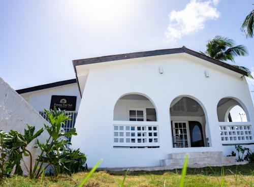 ein weißes Haus mit einer Palme davor in der Unterkunft Puesta del Sol Guest House in San Andrés