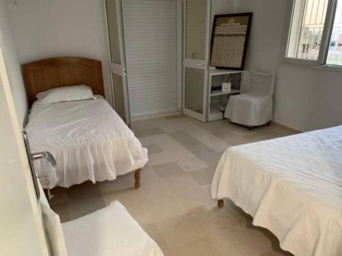 - une chambre avec 2 lits et une chaise dans l'établissement New 3 bedroom condo/plenty parking/15 min to Tunis, à Fouchana