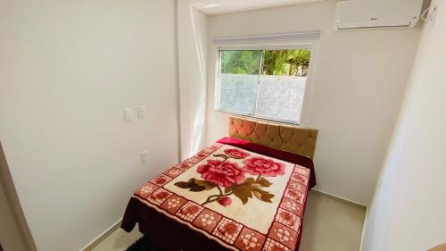 Dormitorio pequeño con cama y ventana en Apê Campeche, en Florianópolis