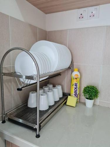 a kitchen counter with a shelf with cups and bleach at 3Storey House 13Pax Family Suite in Bayan Lepas