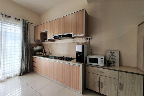 a kitchen with wooden cabinets and a microwave at 3Storey House 13Pax Family Suite in Bayan Lepas