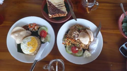 two plates of food on a wooden table at Wina Wani Bungalows Tetebatu in Tetebatu