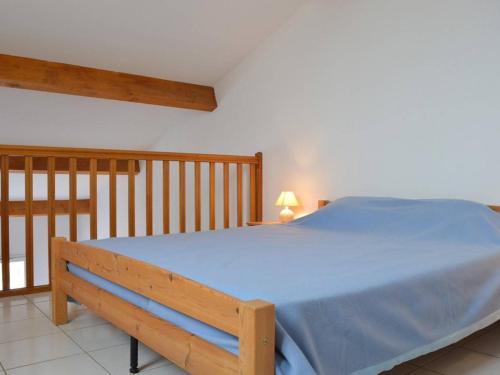 - une chambre avec un lit bleu et une balustrade en bois dans l'établissement Maison 2P avec mezzanine, piscine et parking, à 800m de la plage - Saint-Pierre-la-Mer - FR-1-229D-352, à Saint Pierre La Mer