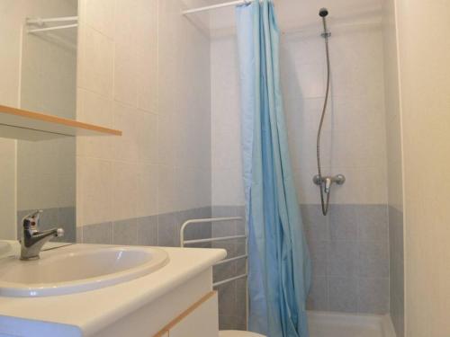 ein Badezimmer mit einem Waschbecken und einer Dusche mit einem blauen Duschvorhang in der Unterkunft Maison Fleury-Saint-Pierre-la-Mer, 2 pièces, 6 personnes - FR-1-229D-352 in Saint Pierre La Mer