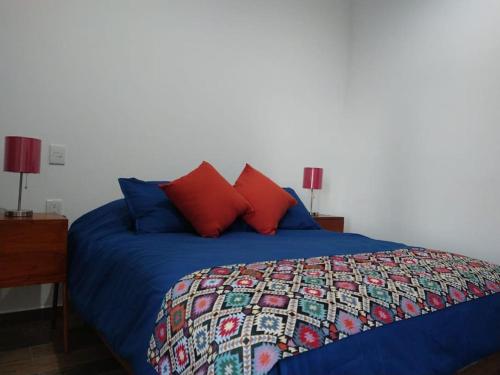 a bedroom with a blue bed with red pillows at Bonito apartamento a pasos del malecón de Mazatlán in Mazatlán