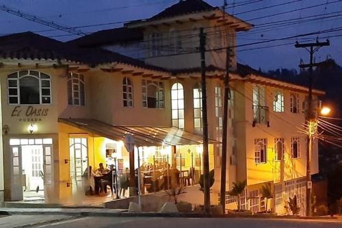 um edifício com pessoas sentadas do lado de fora à noite em El Oasis Fomeque em Fómeque