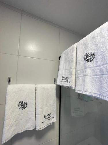 ein Badezimmer mit weißen Handtüchern mit Namen darauf in der Unterkunft Flat ESTUDIO de LUXO - Praia de Muro Alto - Piscinas - Ideal para CASAIS, famílias com crianças - ap COMPLETO - AR COND, WI FI, NETFLIX, ESTACIONAMENTO - 400 mt do MAR in Porto De Galinhas