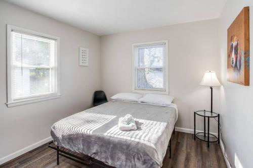a white bedroom with a bed and two windows at Modern & Quiet Suburban Ranch Mins to Dtwn/Stores in East Rochester
