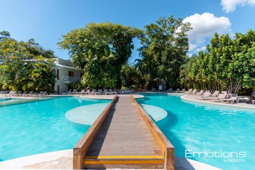 una piscina con un paseo marítimo de madera en un complejo en Beach Apartment Villas Jubey, Emotion access, en Juan Dolio