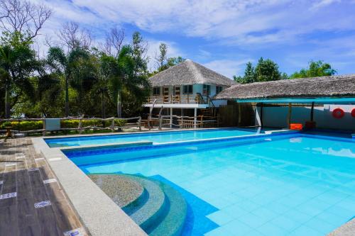 ein Schwimmbad mit einem Haus im Hintergrund in der Unterkunft UNWND BOUTIQUE HOTEL CALATAGAN in Batangas City