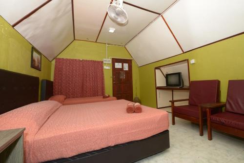 - une chambre avec un lit, une chaise et une télévision dans l'établissement Delta Chenang Resort, à Pantai Cenang