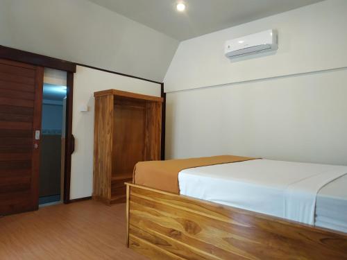 a bedroom with a bed and a wooden door at Bluecoral Bungalows in Gili Meno
