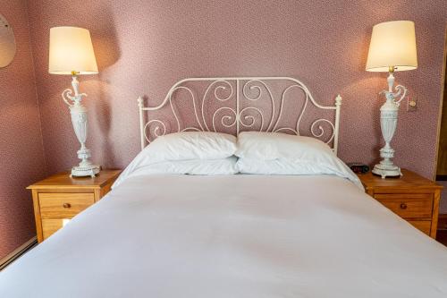 a bedroom with a white bed with two lamps at Albergo Allegria Hotel & Breakfast Restaurant in Windham