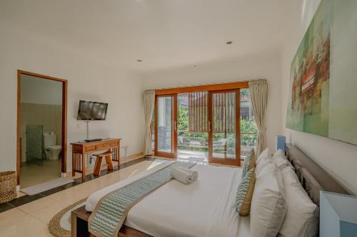 1 dormitorio con 1 cama blanca grande y TV en Villa Alleira Seminyak by Best Deals Asia Hospitality, en Seminyak