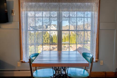 a table and chairs in front of a large window at Albergo Allegria Hotel & Breakfast Restaurant in Windham