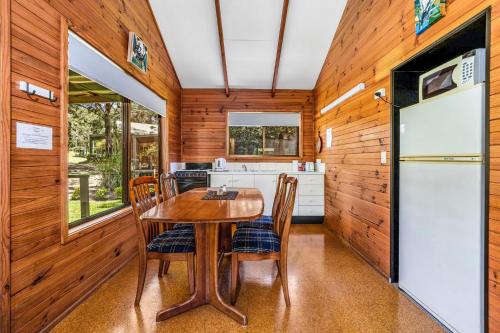 a kitchen with a table and chairs and a refrigerator at Craigies Cabin in Kangaroo Valley