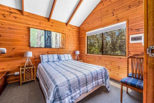 a bedroom with a bed and a desk and a window at Beau Cabin One Bedroom Cabin on Golf Course in Kangaroo Valley