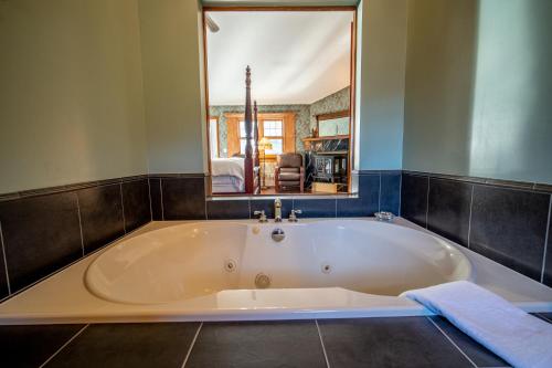 a large bath tub in a bathroom with a mirror at Albergo Allegria Hotel & Breakfast Restaurant in Windham